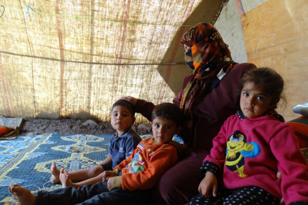 Hala, Omar and Sanad gather around their mother, Amani.Amani  is from a small town in Eastern Ghouta, where all the houses were flattened to the ground. Her father and three of her uncles were killed in front of her very eyes. She recalls her aunt being beaten, raped and then executed under her gaze. While everyone from her town fled, Amani, her husband Khaled and their children stayed in besieged Eastern Ghouta. Life was unbearable. Amani left her husband there to look for a place to protect her children from the airstrikes
She reached As-Suwayda governorate, when it was covered with snow and most people gathered around their heaters, but she couldnt find a shelter for her children. She then headed to Quneitra governorate, where she finally settled in a camp set on rocky land close to the Syrian-Israeli border and distant from any inhabited areas. .Amani has three children, Hala, Omar and Sanad. She lives with them in a small tent that offers little protection from the hot summers and cold winters. Every day, she has to walk a long way to get clean water. With the prevalence of snakes and scorpions, she lives in constant worry for her children
Amani says that Al-Rahma (mercy, in Arabic) Camp has no mercy. It is filled with rocks and thorns, which she spends hours plucking from her childrens feet when they are done playing for the day and dress up their wounds after stumbling upon rocks
My only wish is to have a dignified life with my husband and children, away from the war and this dangerous environment, she says