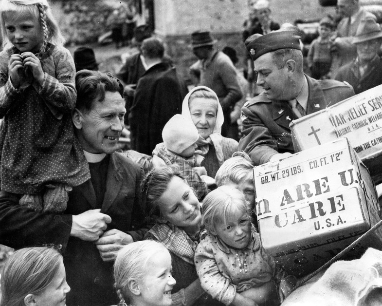 CARE food packages are a welcome gift to the families burned out in a recent fire in Lessach, Austria.  Here, Rev. Franz Esthofer, Pastor of Lessach, receives the packages from Chaplain (Major) Edward J. Saunders, Salzburg area Chaplain.  The parcels were distributed as gifts from the American Women's 